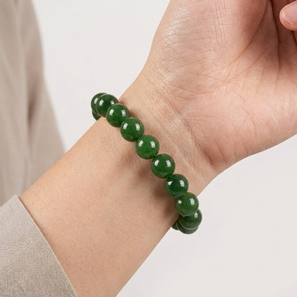 Gros plan d'un poignet portant le bracelet en jadéite verte polie de l'Atelier Wen. Éclat naturel des perles rondes.